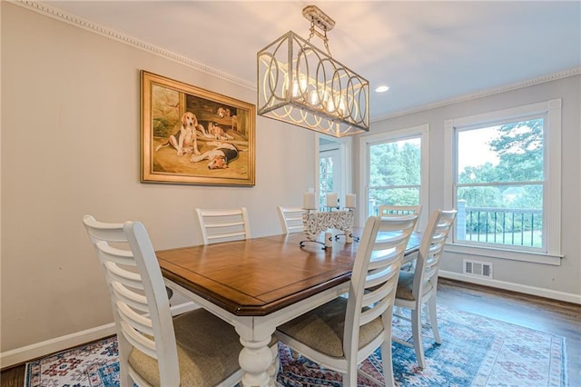 dining room with hardwood / wood-style flooring, crown molding, and an inviting chandelier