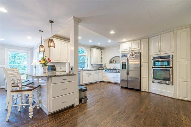 kitchen featuring backsplash, a healthy amount of sunlight, light stone countertops, and stainless steel fridge