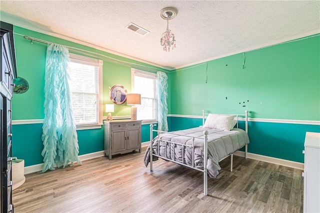 bedroom featuring light hardwood / wood-style flooring, crown molding, and a textured ceiling