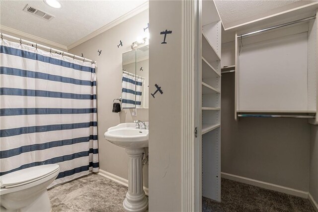 bathroom featuring crown molding, a textured ceiling, toilet, and walk in shower