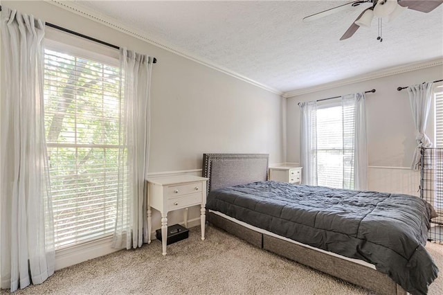 bedroom with a textured ceiling, light carpet, ornamental molding, and ceiling fan