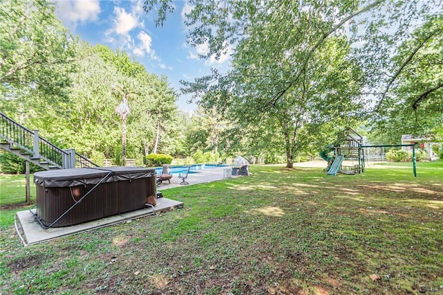 view of yard featuring a playground and a swimming pool with hot tub