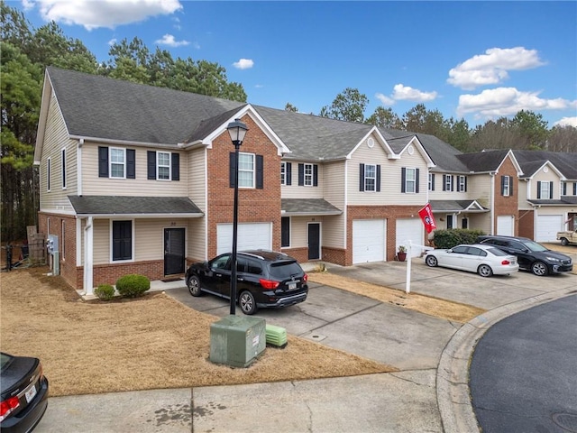 townhome / multi-family property featuring a garage, brick siding, driveway, roof with shingles, and a residential view