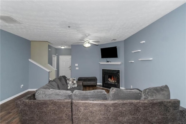 living room with a textured ceiling, dark hardwood / wood-style flooring, and ceiling fan