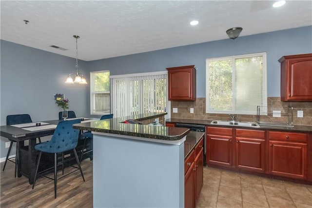 kitchen featuring pendant lighting, decorative backsplash, a center island, and an inviting chandelier