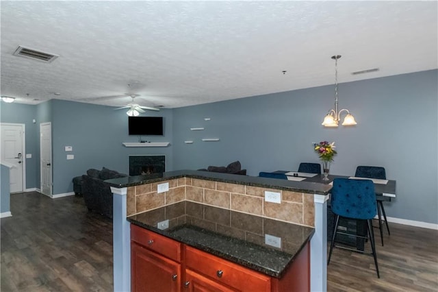 kitchen with a textured ceiling, ceiling fan with notable chandelier, dark hardwood / wood-style floors, and hanging light fixtures