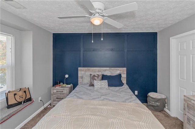 carpeted bedroom with ceiling fan and a textured ceiling