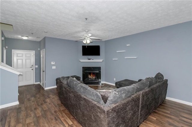 living room with a premium fireplace, dark hardwood / wood-style flooring, ceiling fan, and a textured ceiling