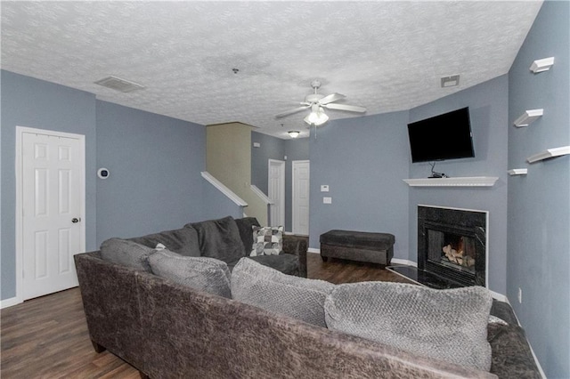 living room with a textured ceiling, dark hardwood / wood-style floors, and ceiling fan