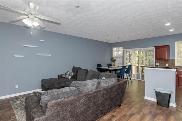 living room featuring ceiling fan, dark wood-type flooring, and a textured ceiling