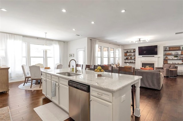 kitchen featuring sink, light stone counters, decorative light fixtures, a center island with sink, and dishwasher