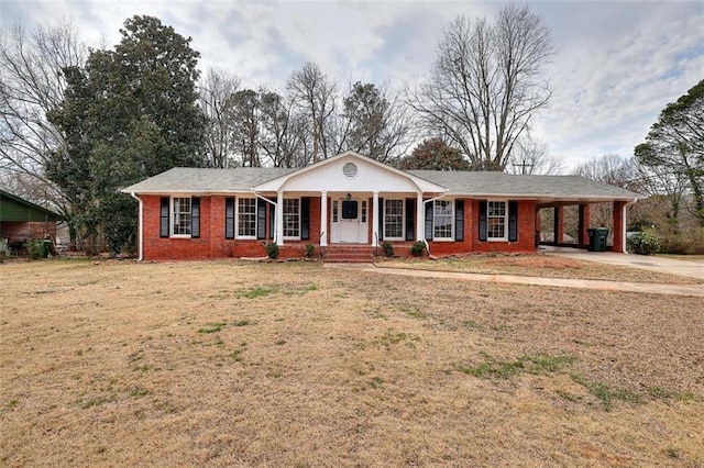 view of front of home featuring driveway, brick siding, covered porch, a carport, and a front yard