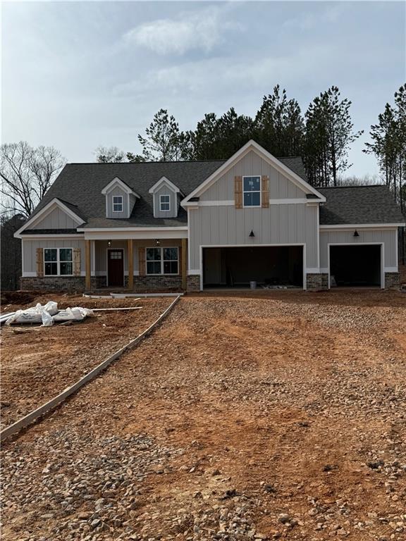 craftsman-style house featuring a garage, stone siding, driveway, and board and batten siding