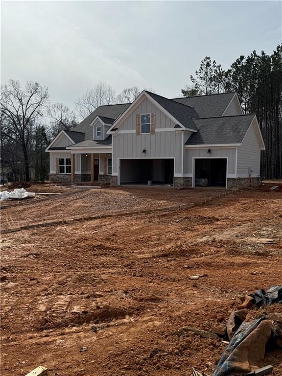 craftsman inspired home with stone siding, a shingled roof, covered porch, and board and batten siding