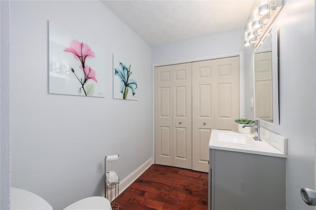 bathroom with toilet, baseboards, wood finished floors, and vanity