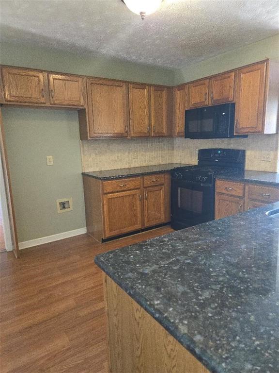 kitchen featuring black appliances, dark hardwood / wood-style floors, and decorative backsplash