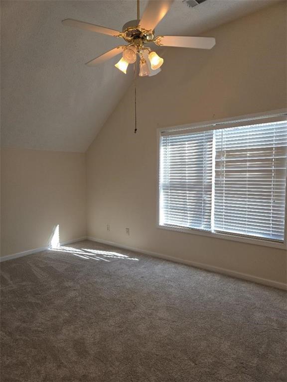 additional living space featuring a textured ceiling, carpet floors, ceiling fan, and lofted ceiling