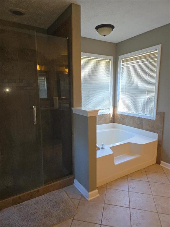 bathroom featuring tile patterned flooring, a textured ceiling, and plus walk in shower