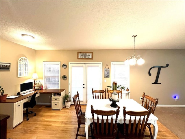 dining area with a textured ceiling, light wood-style flooring, a chandelier, baseboards, and french doors