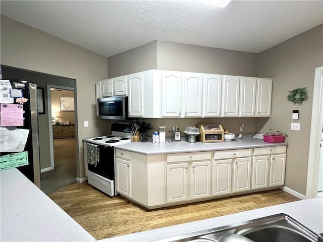 kitchen featuring light countertops, white cabinets, stainless steel appliances, and light wood finished floors