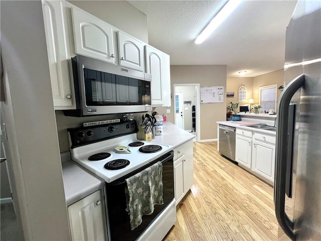 kitchen with a textured ceiling, light countertops, appliances with stainless steel finishes, white cabinetry, and light wood-style floors