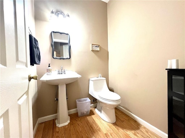 bathroom featuring baseboards, toilet, and wood finished floors