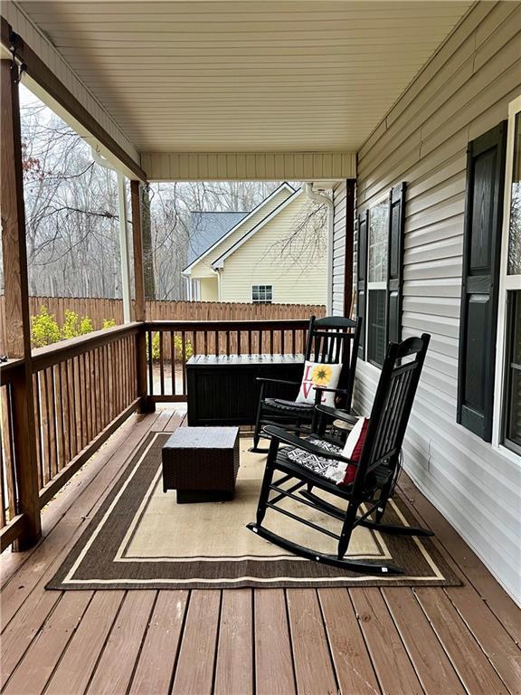 wooden terrace featuring an outdoor hangout area and fence