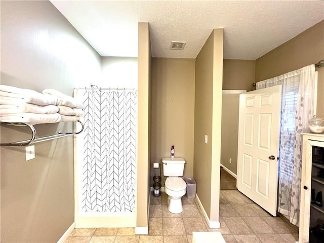 full bathroom featuring a textured ceiling, visible vents, baseboards, toilet, and curtained shower