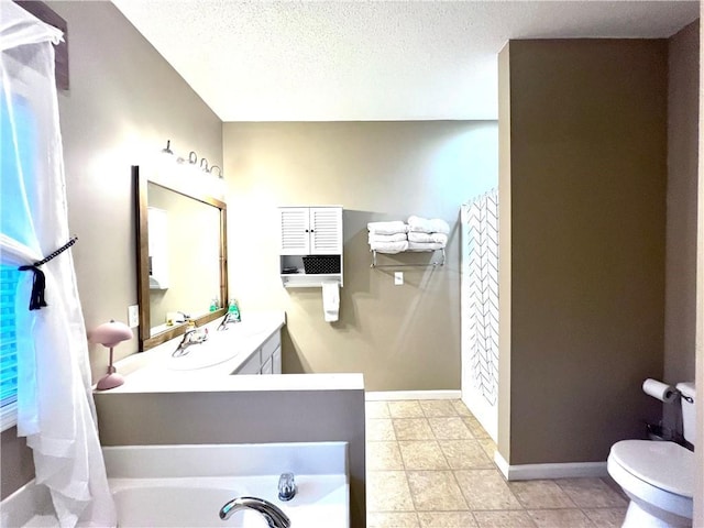 bathroom with vanity, toilet, baseboards, a textured ceiling, and a tub to relax in