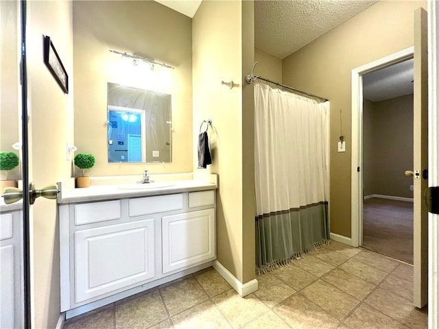 bathroom with vanity, a shower with curtain, a textured ceiling, tile patterned flooring, and baseboards