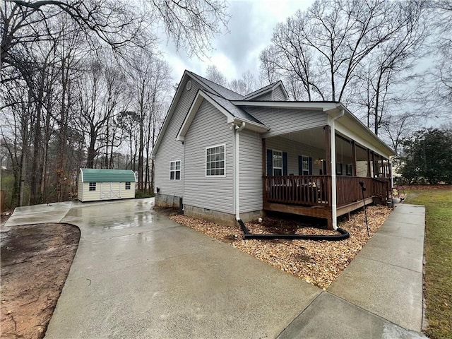 view of side of property with crawl space, driveway, covered porch, and an outdoor structure