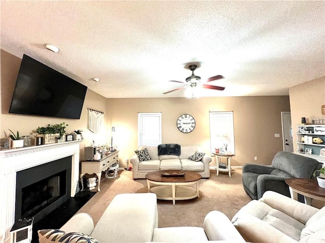 carpeted living area with a ceiling fan, a fireplace with flush hearth, baseboards, and a textured ceiling