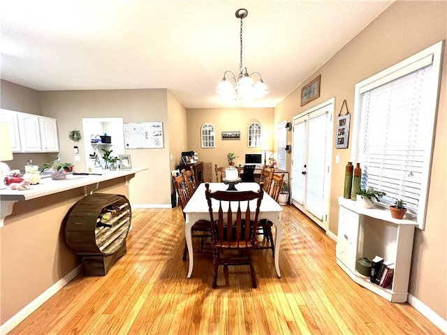dining area featuring light wood finished floors, baseboards, and a chandelier