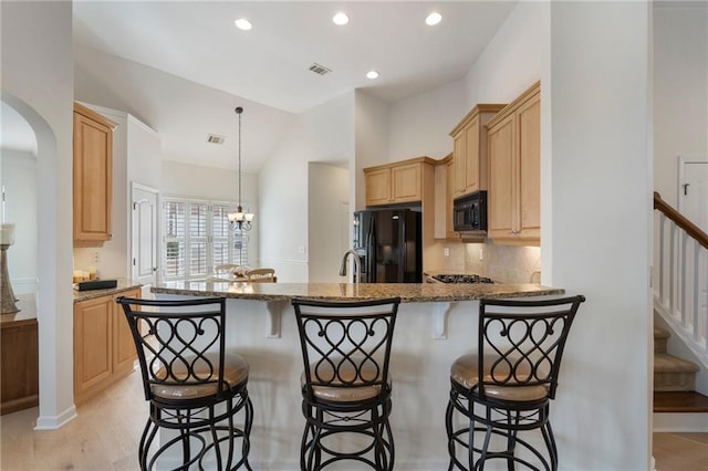 kitchen featuring light brown cabinets, visible vents, a peninsula, arched walkways, and black appliances