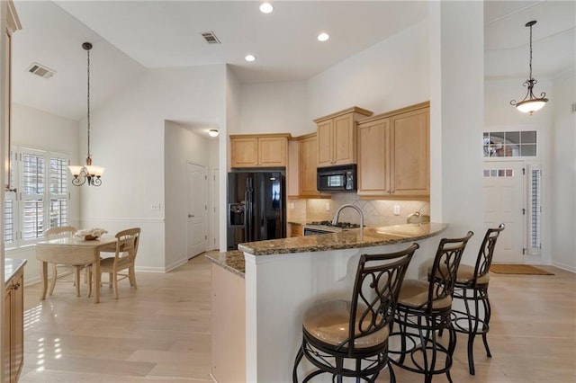 kitchen with visible vents, high vaulted ceiling, black appliances, light brown cabinets, and dark stone countertops