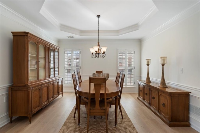 dining space featuring a tray ceiling, visible vents, a wealth of natural light, and wainscoting