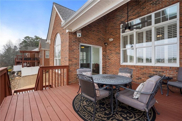 wooden terrace featuring outdoor dining space and a ceiling fan