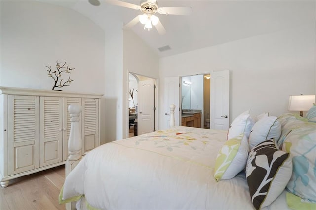 bedroom featuring wood finished floors, visible vents, arched walkways, vaulted ceiling, and connected bathroom