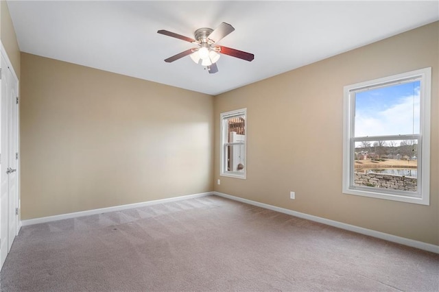 unfurnished room featuring a ceiling fan, baseboards, and light carpet