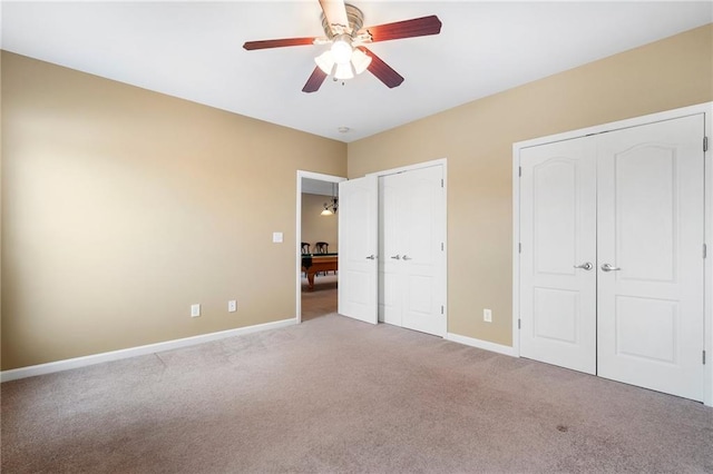 unfurnished bedroom with two closets, baseboards, carpet, and ceiling fan