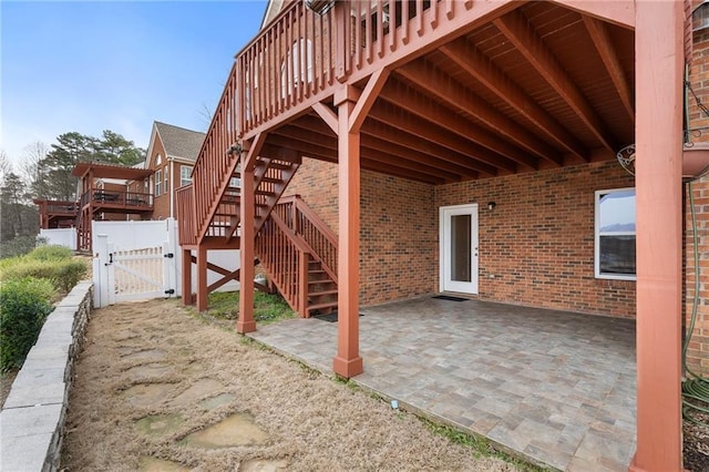 view of patio / terrace featuring stairway, a wooden deck, fence, and a gate