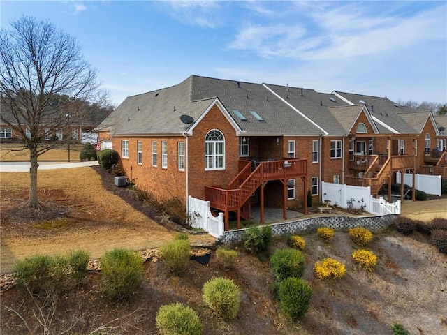 rear view of property featuring stairway, central AC unit, fence, a deck, and brick siding