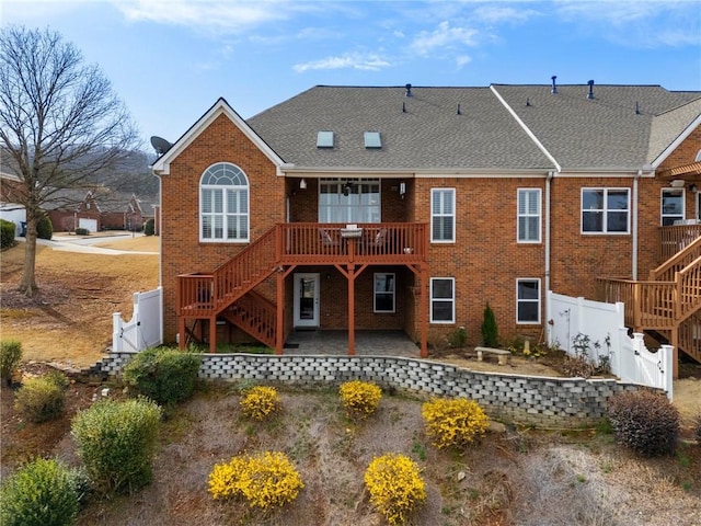 rear view of property with brick siding, a patio area, stairs, and a gate