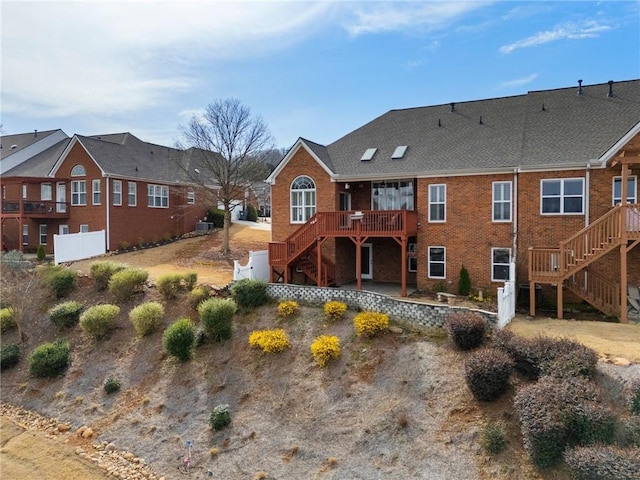 rear view of property with stairway, brick siding, and a wooden deck