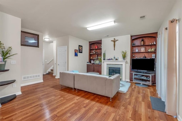 2545 Gatewater Ct, Cumming, GA 30040 - living area featuring light wood-style floors, a glass covered fireplace, stairway, and baseboards
