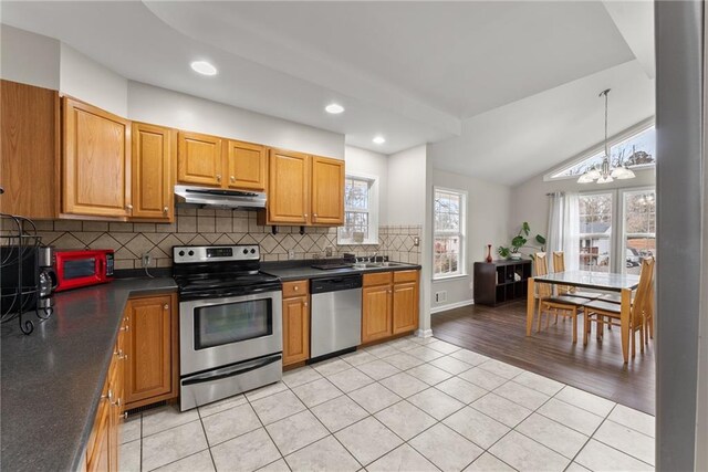 1283 Woodleigh Rd SW, Marietta, GA 30008 - kitchen featuring appliances with stainless steel finishes, vaulted ceiling, light tile patterned floors, an inviting chandelier, and hanging light fixtures