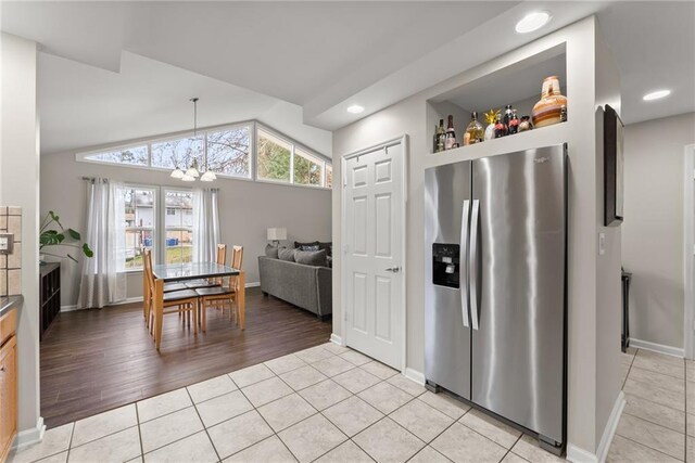 1283 Woodleigh Rd SW, Marietta, GA 30008 - kitchen with stainless steel fridge with ice dispenser, light tile patterned floors, lofted ceiling, and an inviting chandelier