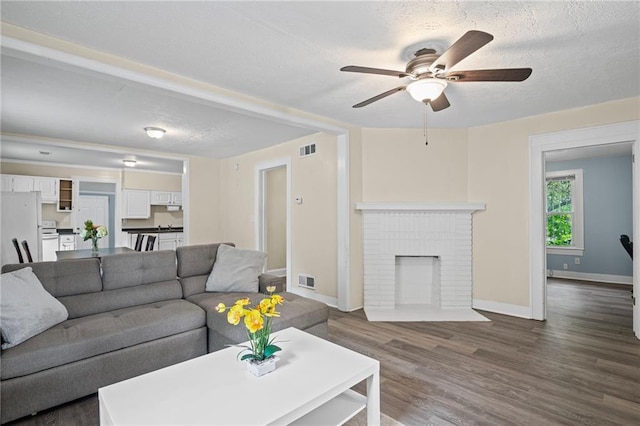 1591 Jonesboro Rd SE, Atlanta, GA 30315 - living room with a ceiling fan, a textured ceiling, dark wood-style floors, baseboards, and a brick fireplace