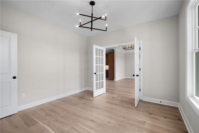 unfurnished dining area with a notable chandelier, french doors, and light hardwood / wood-style flooring