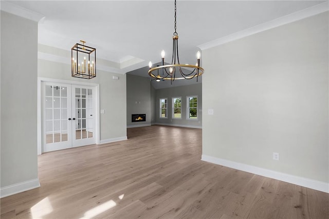 unfurnished dining area with french doors, a notable chandelier, and light wood-type flooring